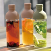 Three glass bottles with colorful infusions on a wooden surface