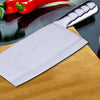 stainless steel knife on top of cutting board and next to red peppers