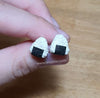 Hand holding pair of onigiri earrings